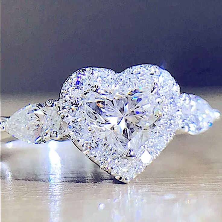 a heart shaped diamond ring with three pear shaped diamonds