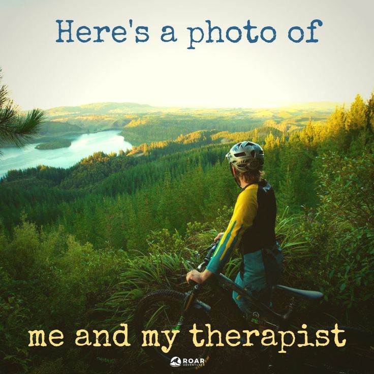 a man riding a bike on top of a lush green hillside next to a lake