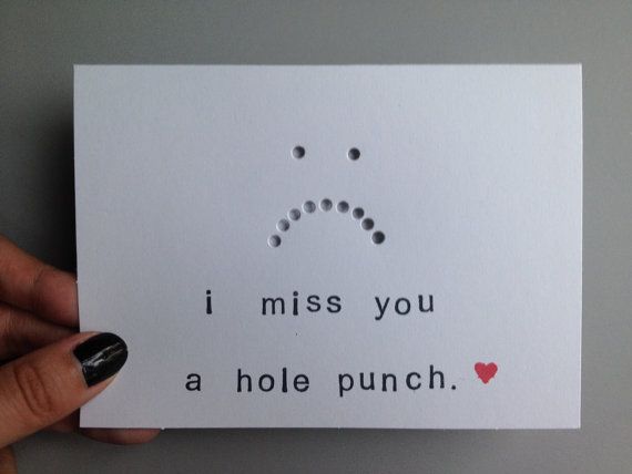 a hand holding up a card that says i miss you a hole punch