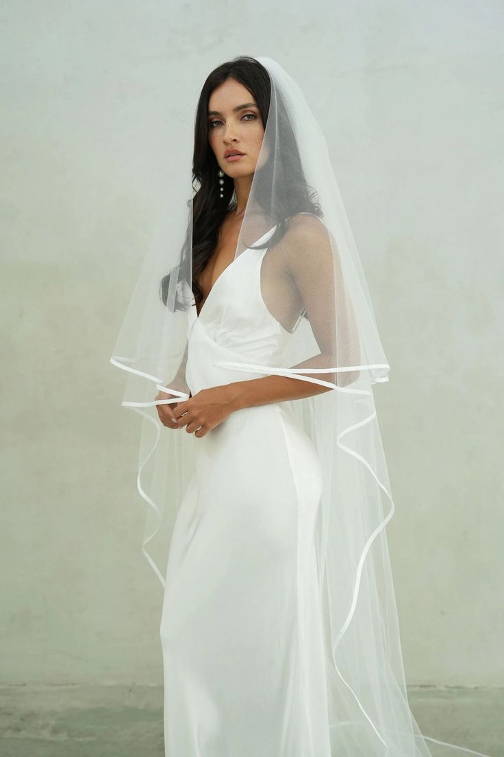 a woman in a white wedding dress with a veil on her head and one arm