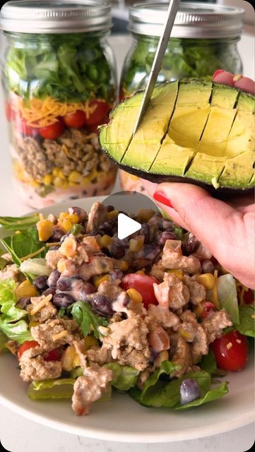 a person holding an avocado over a salad