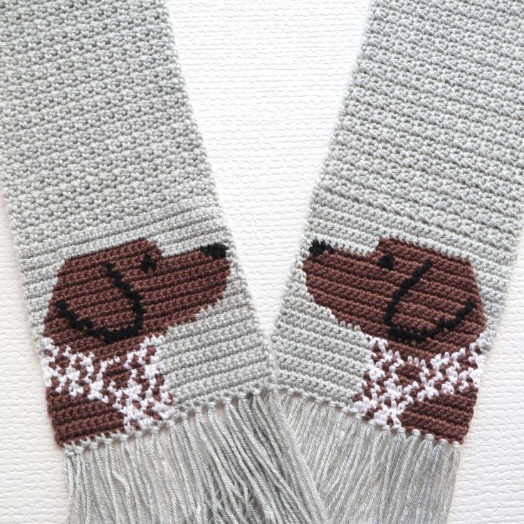 two crocheted scarfs with brown and white dogs on them, one in the middle