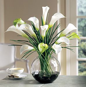 a vase filled with white flowers sitting on top of a table next to a cup