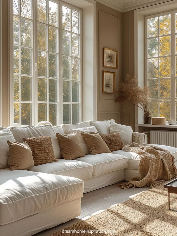 a living room filled with lots of white furniture next to large windows covered in sunlight