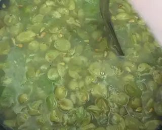 green beans are cooking in a pot with a spoon