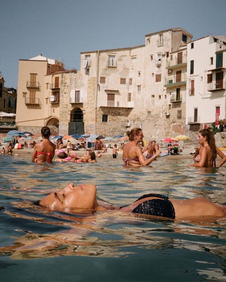 some people are swimming in the water near buildings