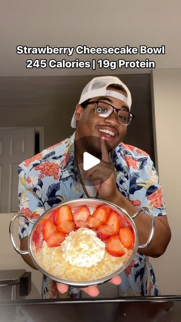 a man holding a bowl of food with strawberries in it and pointing to the camera