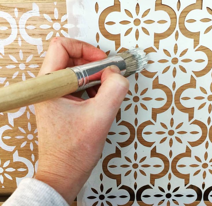 a person using a brush to paint a decorative wall