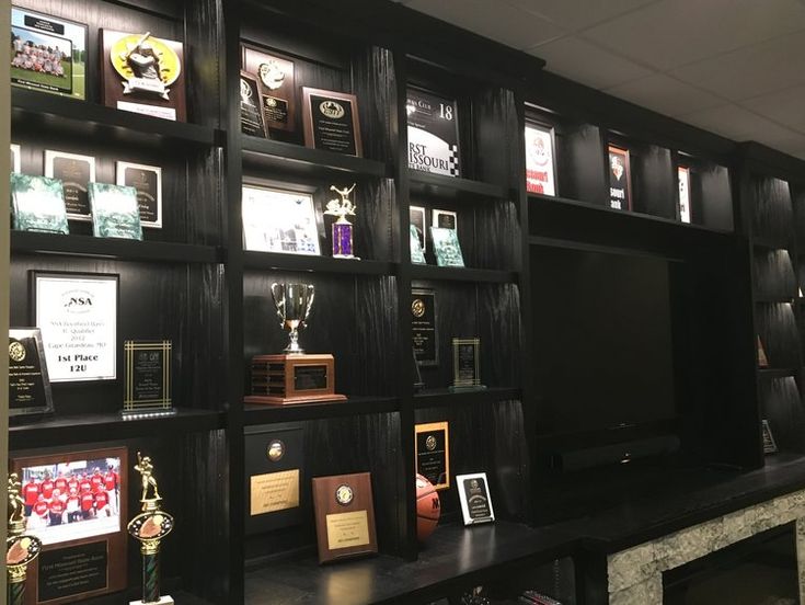 there are many trophies and plaques on the shelves in this room that is decorated with black wood