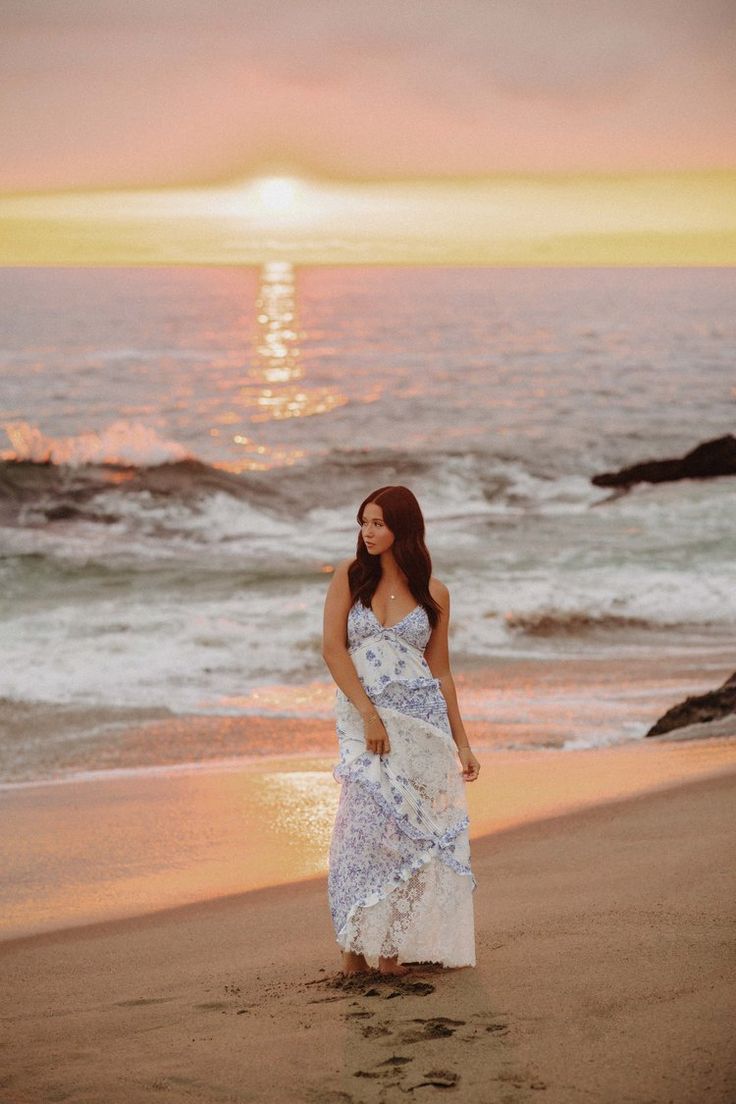 a woman standing on top of a beach next to the ocean