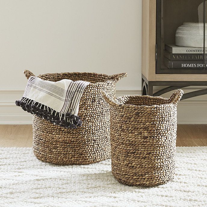 two woven baskets sitting on top of a white rug