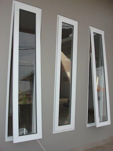 three windows with white frames on the side of a wall in front of a building