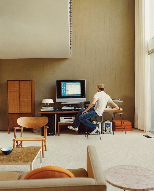 a man sitting in front of a tv on top of a wooden table next to a window