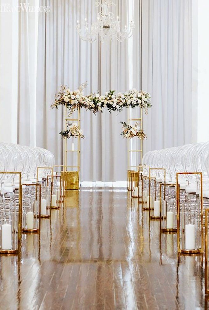 the aisle is lined with gold chairs and white flowers