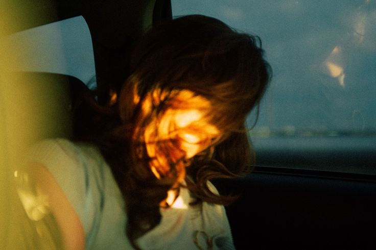 a woman sitting in the back seat of a car with her head out the window