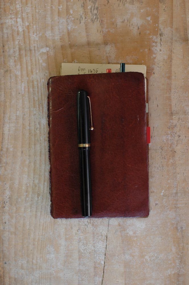 a notebook with a pen on top of it sitting on a wooden table next to a notepad