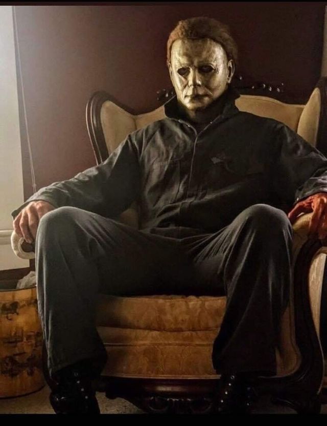 a man sitting on top of a chair wearing a creepy mask