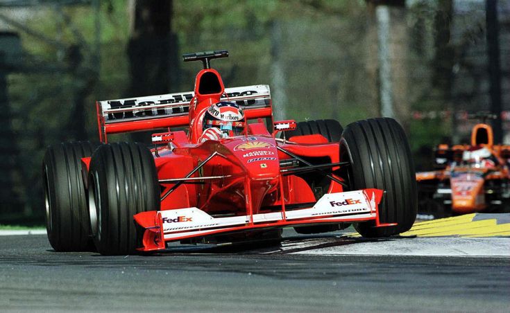 a man driving a red race car on top of a track