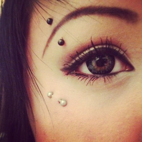 a woman's eye with piercings on it