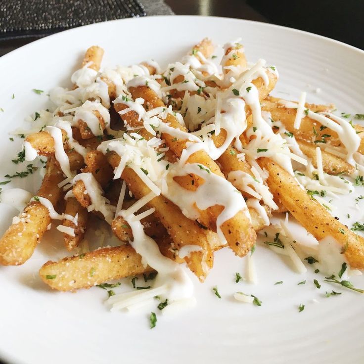 a white plate topped with french fries covered in grated cheese and parmesan