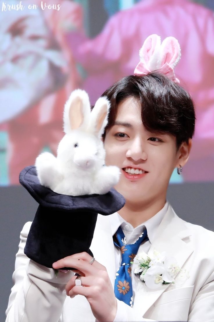 a young man holding up a stuffed animal rabbit