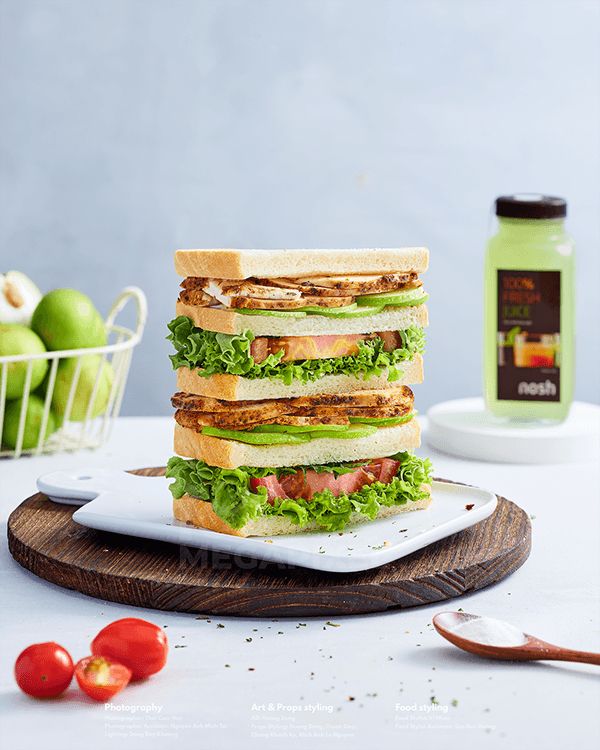 a stack of sandwiches sitting on top of a cutting board next to tomatoes and other fruits