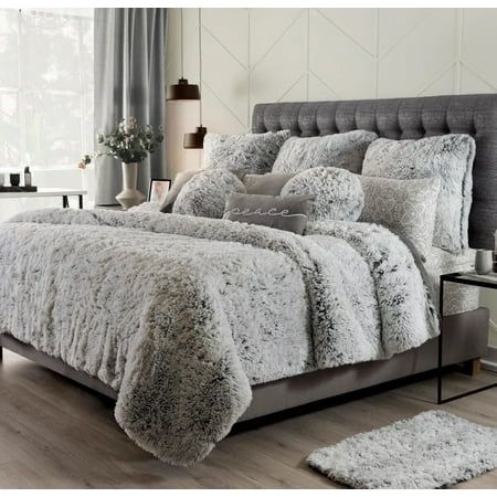 a bed with white and grey comforters in a room