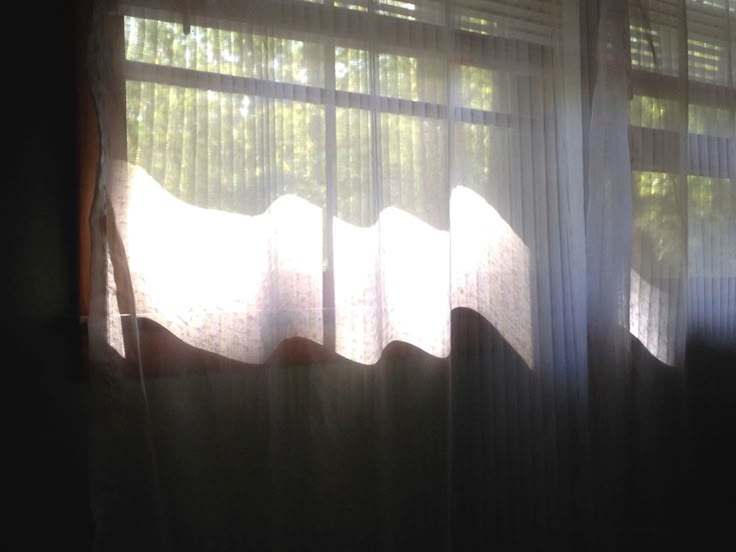 the sun is shining through some curtains