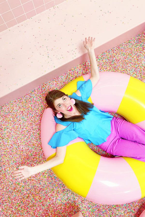 a woman laying on top of an inflatable pool float with sprinkles