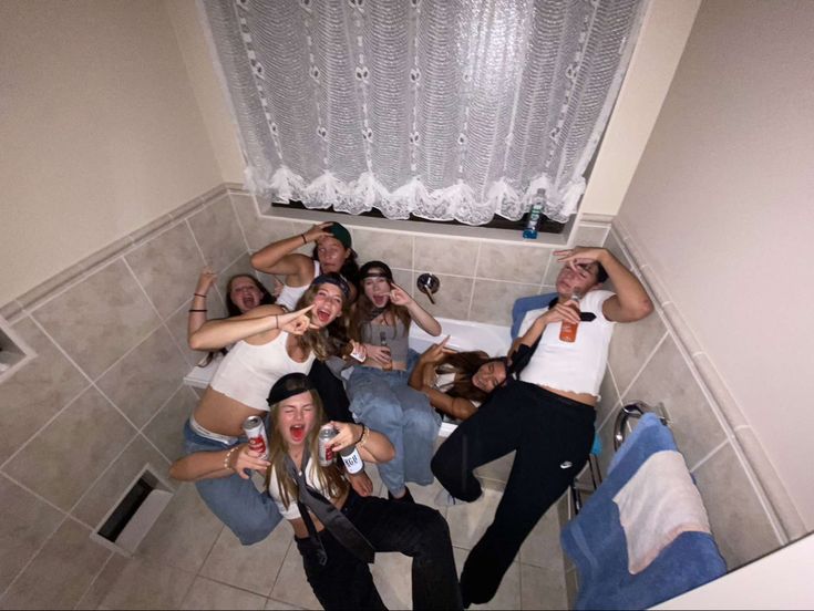 a group of young people sitting on the floor drinking beer and having fun with each other