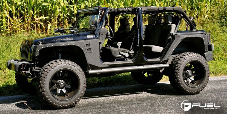 the jeep is parked on the side of the road in front of some corn stalks