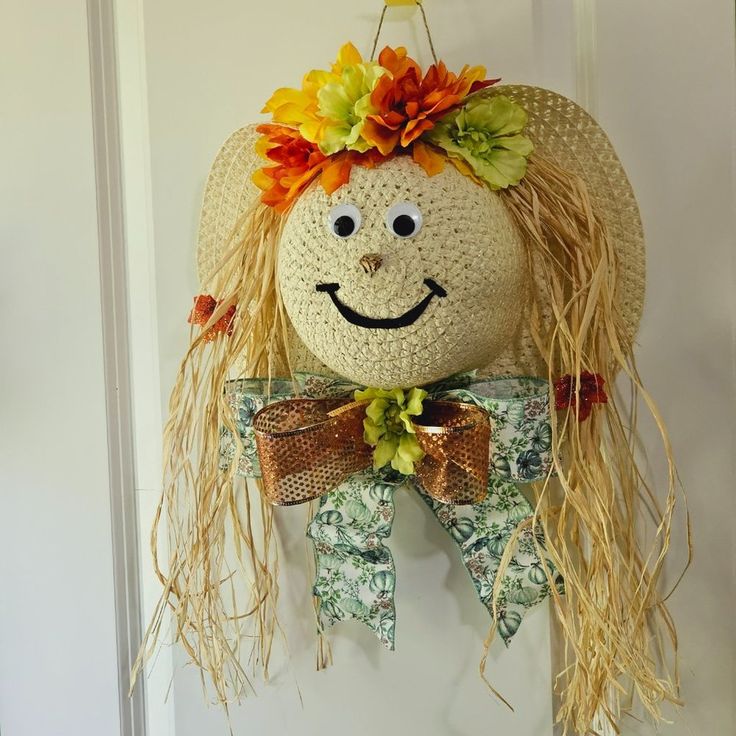 a crocheted scarecrow head hanging on a door with flowers in it's hair