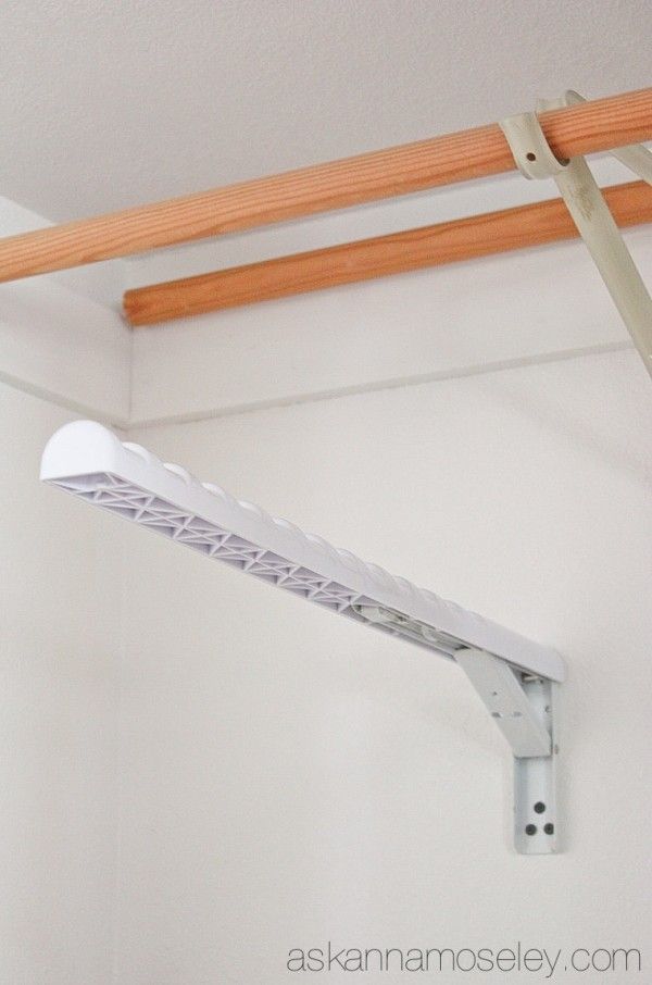 a white shelf with some clothes hanging from it's sides and a wooden rail in the background