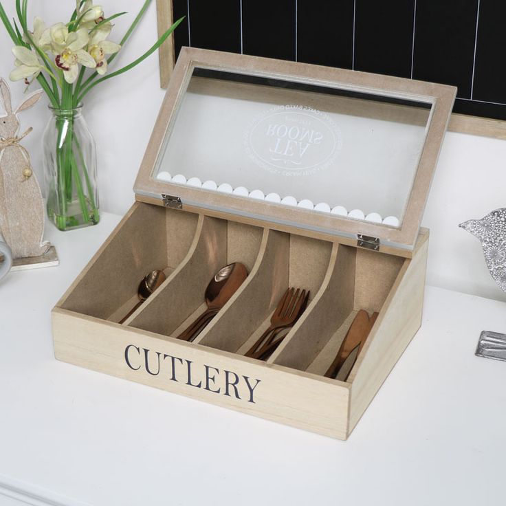 an open wooden box with four pairs of shoes in it sitting on a white counter