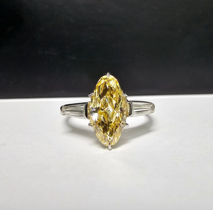 Lively Fancy Intense Orangy Yellow ‘Moval’ Diamond; cross between a Marquise and an Oval Color looks mainly yellow, small hint of orange Tapered Baguette Side Diamonds Set in Platinum & 18K Gold Yellow Diamond Baguette Ring, Yellow Marquise Diamond Ring, Croatian Summer, Manifest Board, Fancy Yellow Diamond Ring, Marquise Wedding Ring, Yellow Diamonds Engagement, Yellow Diamond Ring, Yellow Diamond Engagement Ring