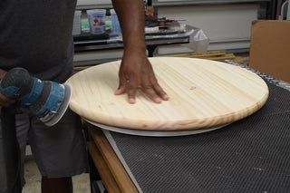 a man sanding on top of a table with a circular object in front of him