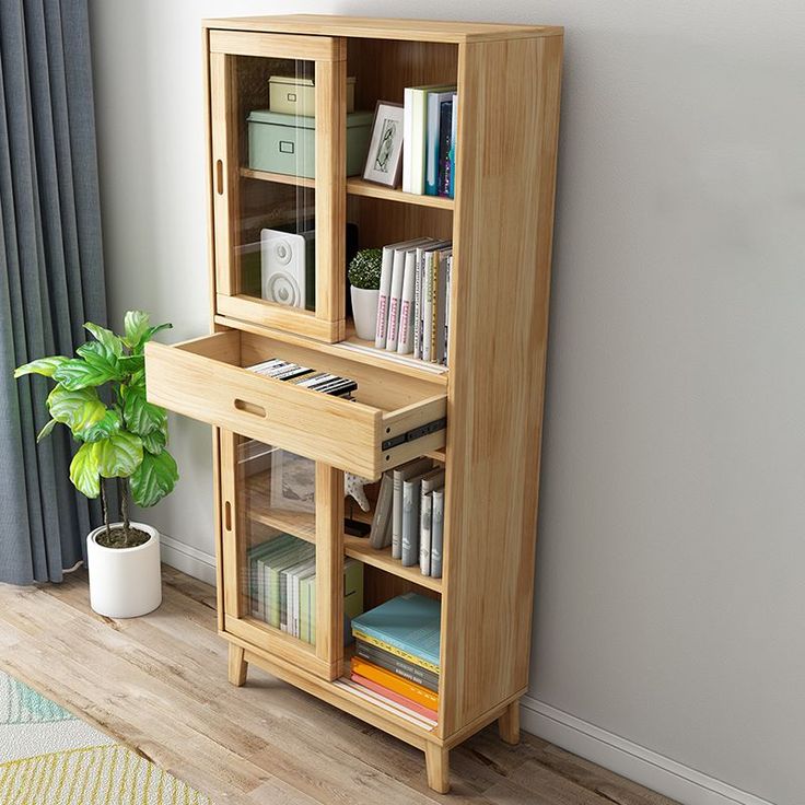 a wooden bookcase with books on it next to a potted plant