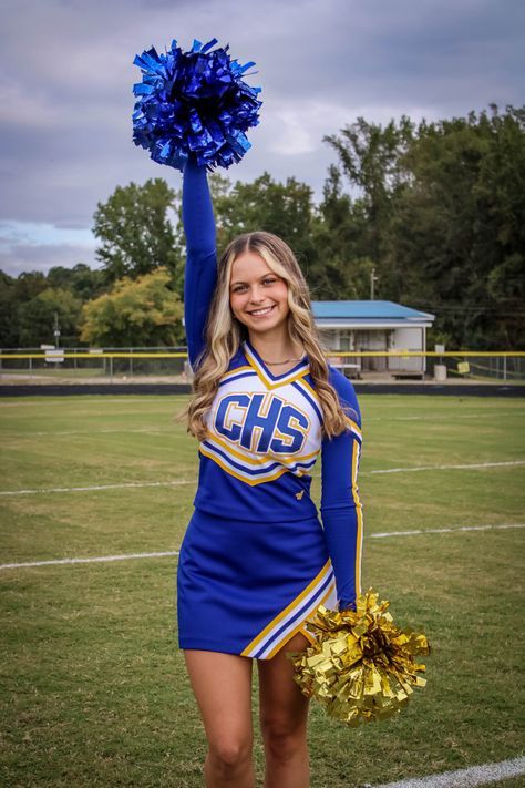 a cheerleader is holding her pom - poms up in the air on a football field