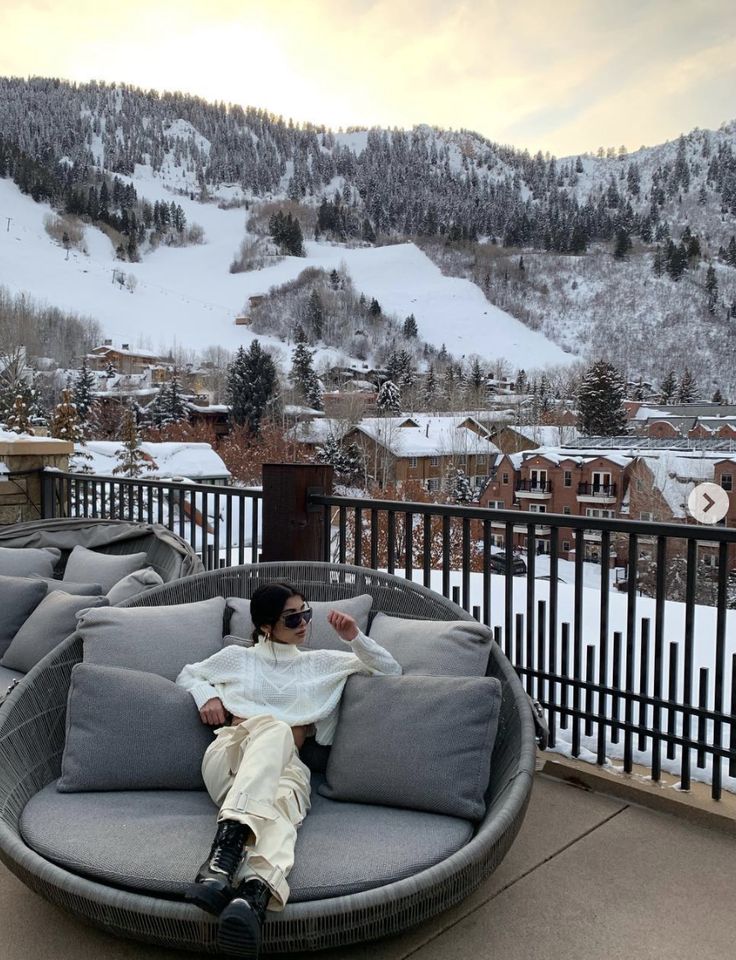 a man sitting on top of a gray couch next to a snow covered mountain range