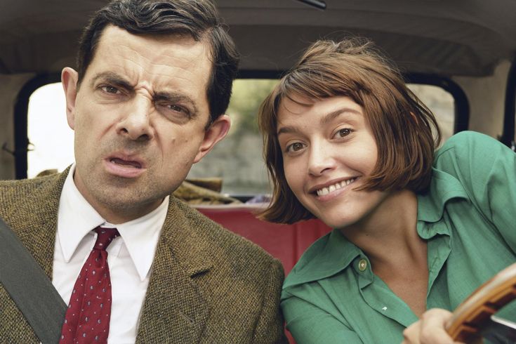 a man and woman sitting in the back of a car