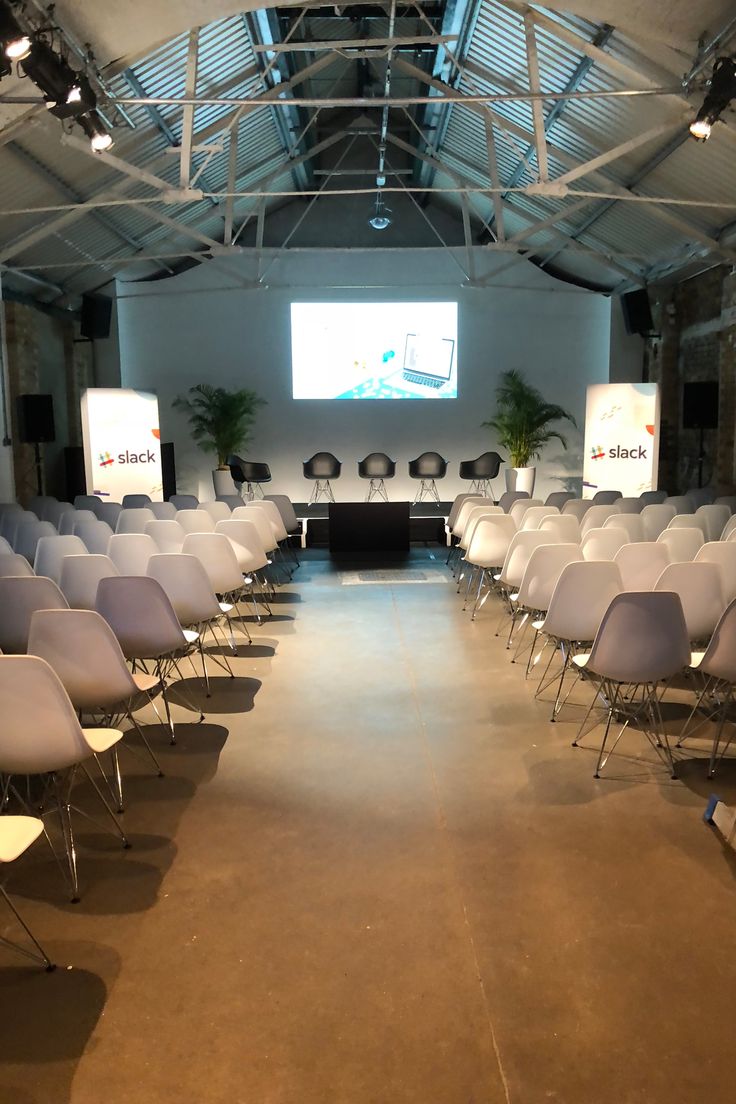 an empty conference room with chairs and projector screen in the back drop off area