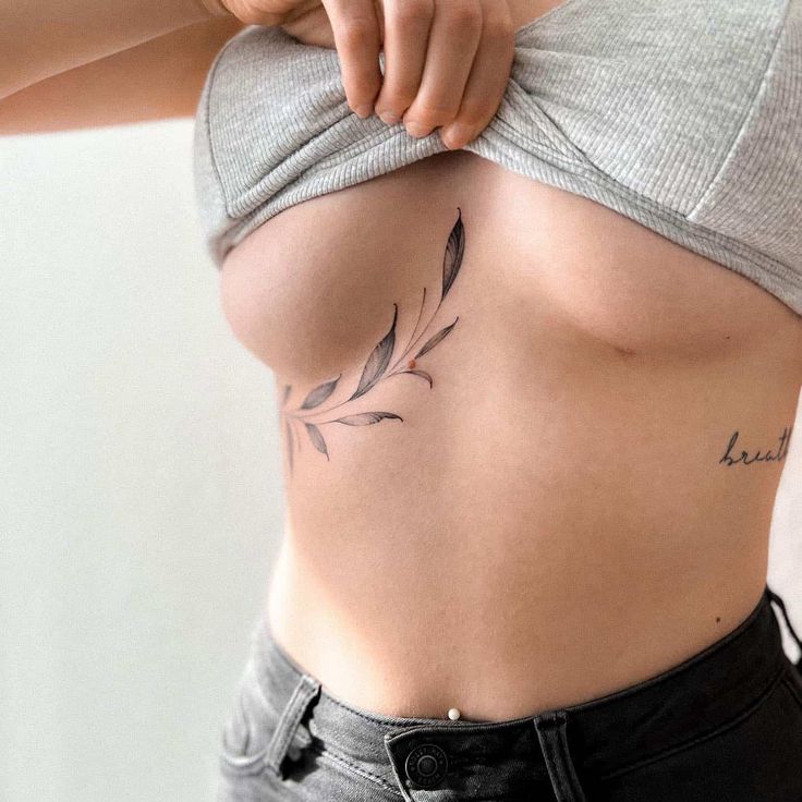 a woman's stomach with tattoos on it and a leaf tattoo on the side