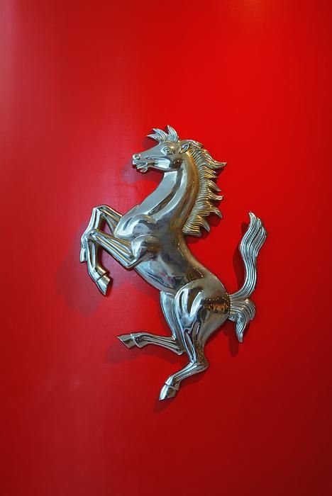 a silver horse on a red background with the word ferrari written in it's center