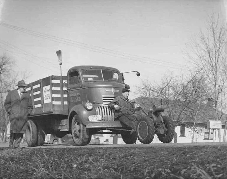 an old black and white photo of two men standing next to a truck