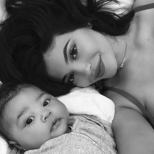 a woman laying on top of a bed next to a baby