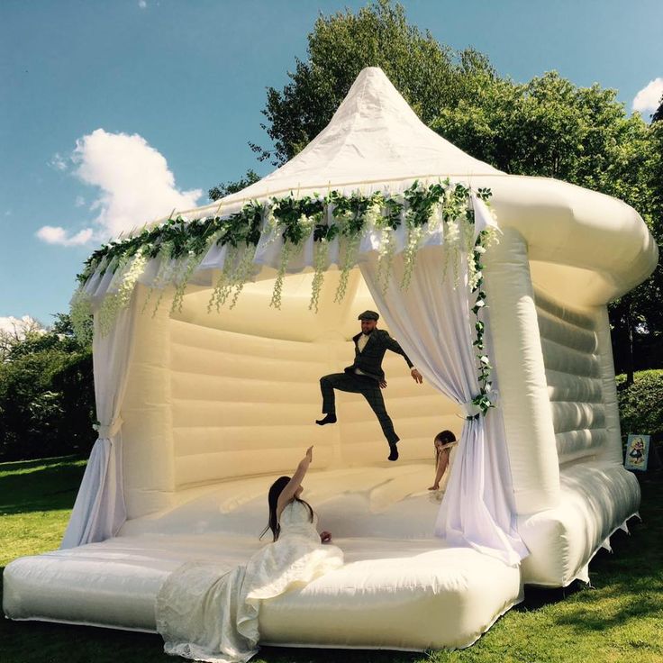 an inflatable wedding tent with two people jumping on the bed and one person laying down