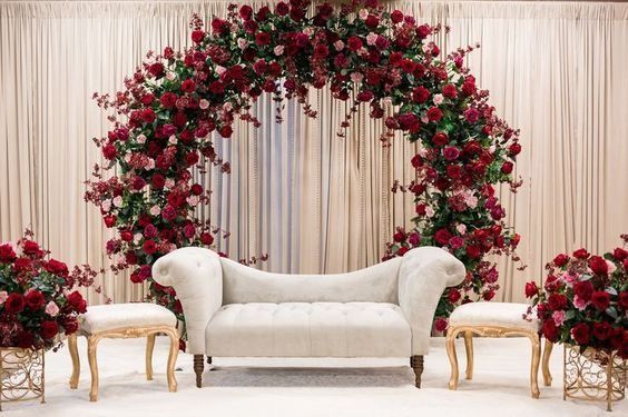 a white couch sitting under a red rose covered arch