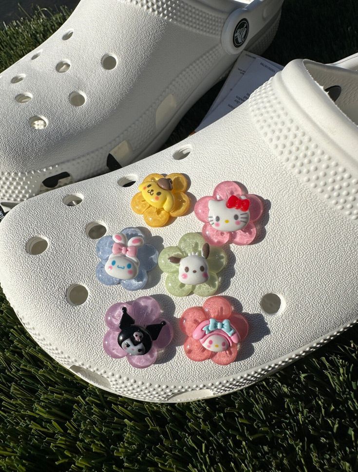 a pair of crocs with hello kitty buttons on them sitting in the grass