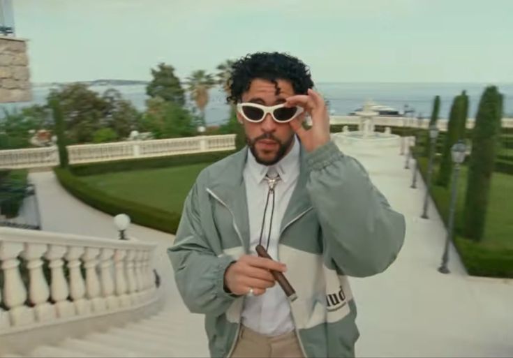 a man wearing sunglasses is standing in front of some stairs and looking at the camera