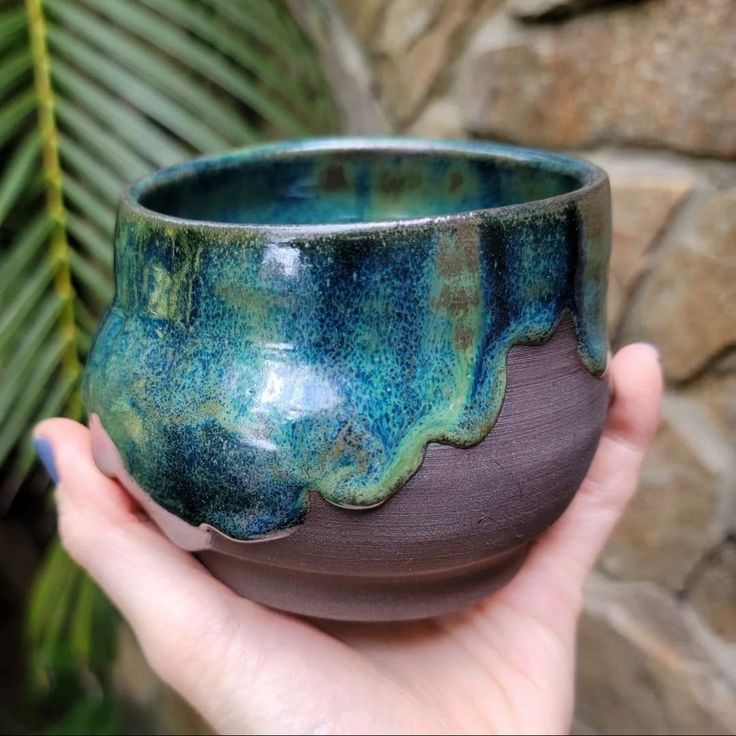 a hand holding a blue and green ceramic bowl